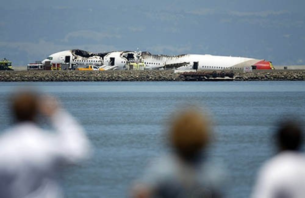 Onlookers view the Asiana Airlines Boeing 777 that crashed on landing at San Francisco International Airport on Saturday. There were about 300 people on board, two of which died as a result of the crash. MCT PHOTO
