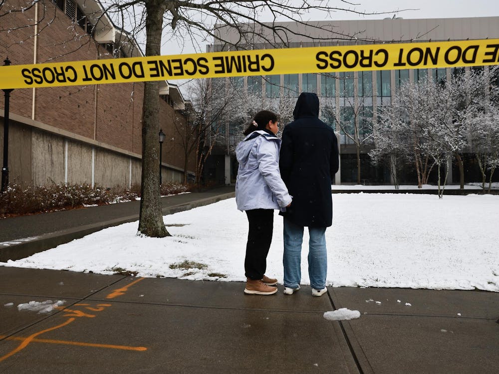 PROVIDENCE, RHODE ISLAND - DECEMBER 14: People pause outside of the engineering and physics building at Brown University, the site of a mass shooting yesterday that left at least two people dead and nine others injured, on December 14, 2025 in Providence, Rhode Island. A suspect in the shooting was detained overnight at a hotel in a nearby community following a manhunt across the prestigious university and the greater Providence area. The shooting took place around 4 p.m. on Saturday as students were preparing for exams and the holiday break. (Photo by Spencer Platt/Getty Images)