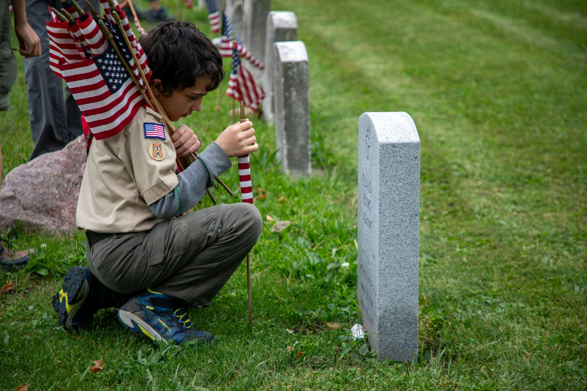A member of Boy Scouts Troop 22 helps place flags at different gravesites in Beech Grove Cemetery in Muncie, Indiana, May 20. Trinity Rea, DN.