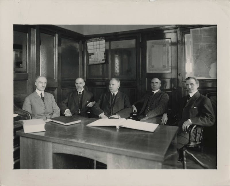 Ball State University founders, George Ball, Lucius Ball, Frank Ball, Edmund Ball and William Ball, sit around a desk. The five Ball brothers bought buildings and grounds of the Muncie National Institute in 1918 and gave the college facilities to the state of Indiana. The college became the Eastern Division of the Indiana State Normal School. Digital Media Repository Photo&nbsp;