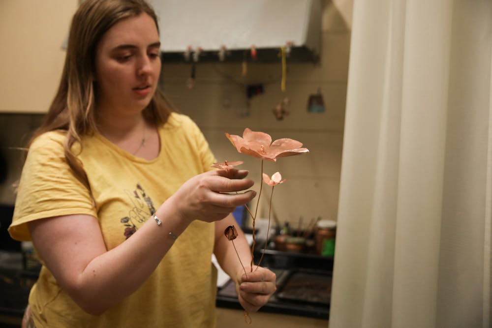 Fourth-year metal-smithing concentration student Kelsey Bobrowski explains the process of making the copper flowers for her thesis project in the metals studio April 11. Jacy Bradley, DN