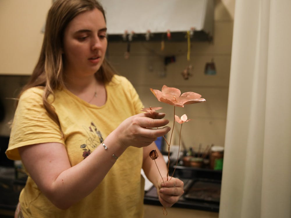 Fourth-year metal-smithing concentration student Kelsey Bobrowski explains the process of making the copper flowers for her thesis project in the metals studio April 11. Jacy Bradley, DN