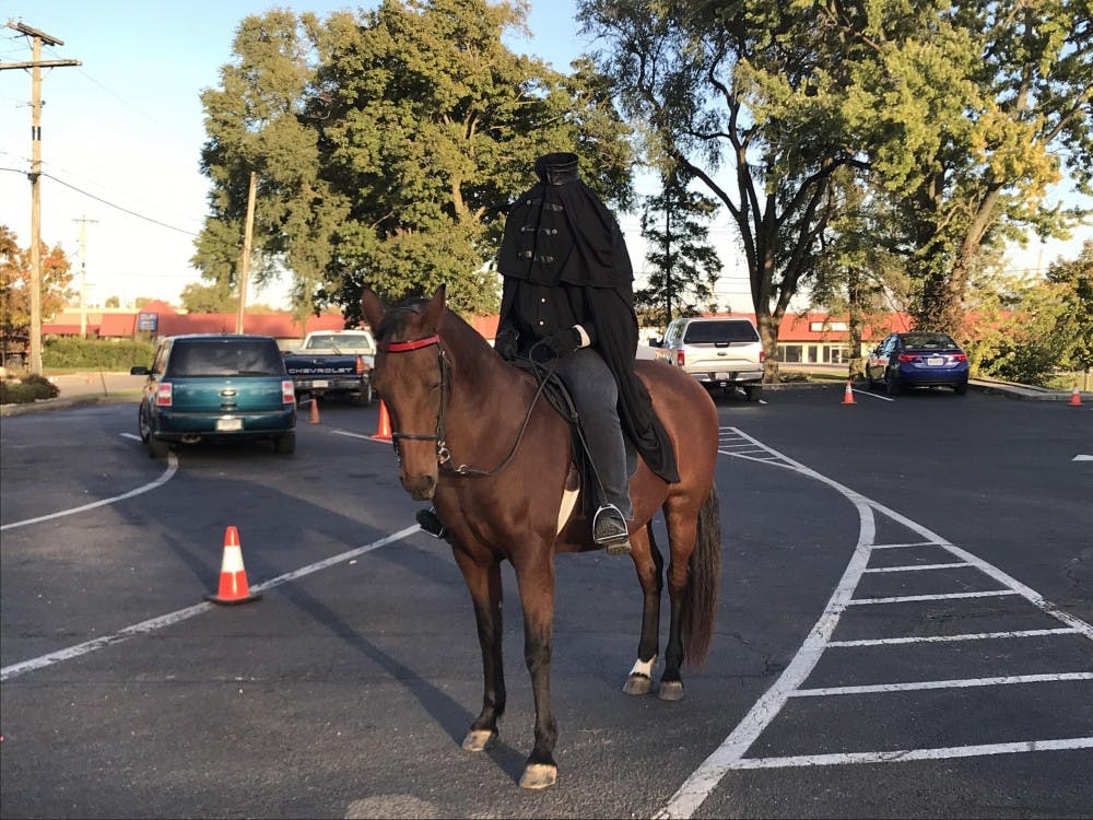 Megan Smith waits for children in the parking lot of McDonalds on McGalliard during their Family Night event Oct. 24, 2018, in Muncie. Smith has been performing as the Headless Horseman since she was 14 years old. Mary Eber,DN