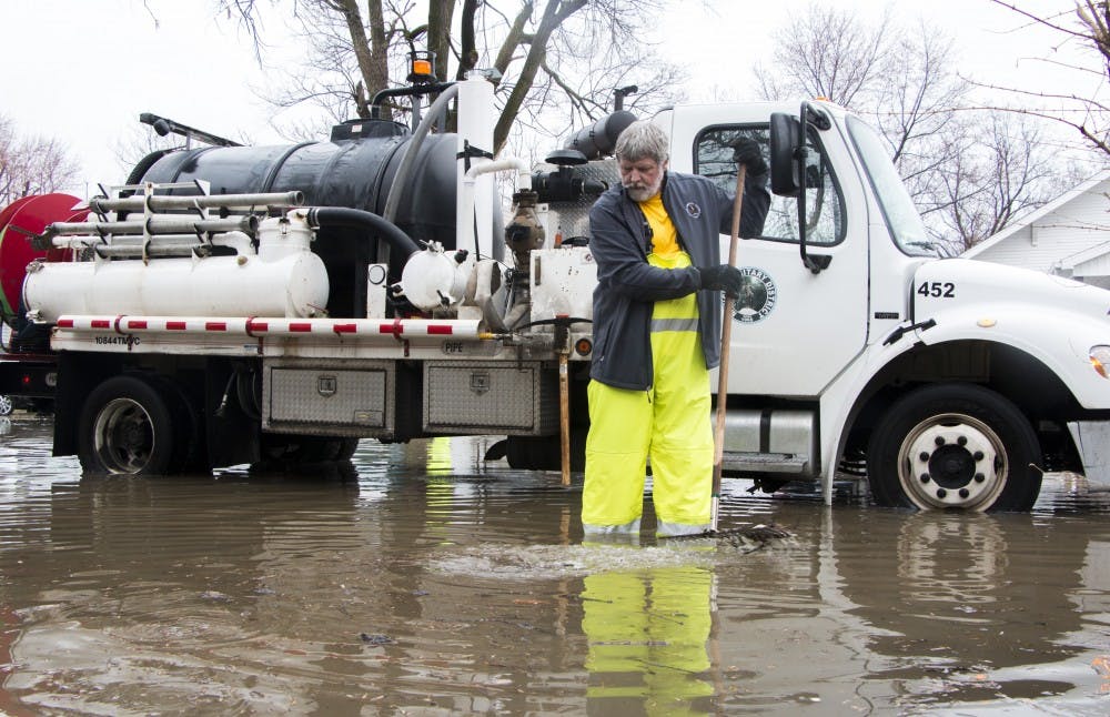 Randy Wright, a member of the Muncie Sanitary District, uses a rake April 3 to clear the sewer drains on Ball Avenue. Wright worked to fix draining issues from the heavy rains .DN PHOTO TAYLOR IRBY