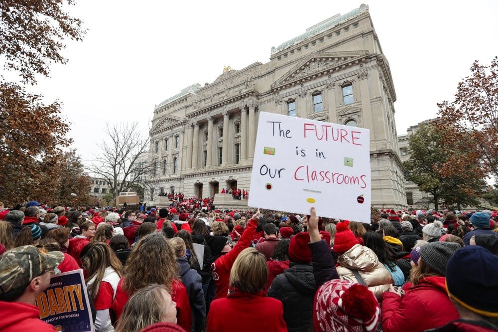 <p>Thousands of Indiana teachers wearing red surround the Statehouse in Indianapolis, Tuesday, Nov. 19, 2019 for a rally calling for further increasing teacher pay in the biggest such protest in the state amid a wave of educator activism across the country. Teacher unions says about half of Indiana's nearly 300 school districts are closed while their teachers attend Tuesday's rally while legislators gather for 2020 session organization meetings. <strong>(AP Photo/Michael Conroy)</strong></p>