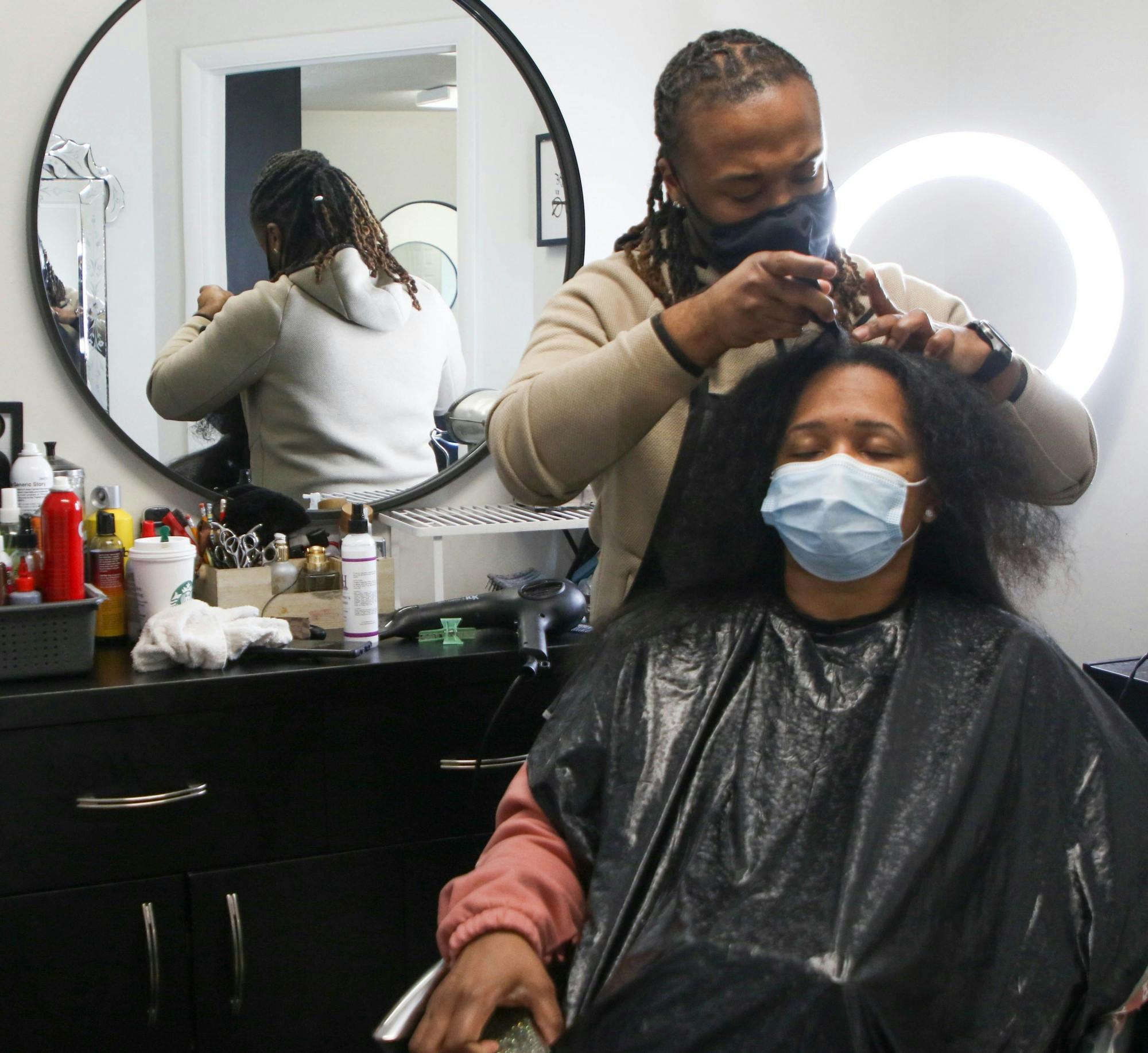 Che Hopkins, owner of Meraki Style Studio, parts Rachelle Joyner’s hair to blow dry for a silk press March 12, 2021. Joyner said she drove from Indianapolis, Indiana, to get her hair down by Hopkins as he has been her stylist for 13 years. Sumayyah Muhammad, DN.