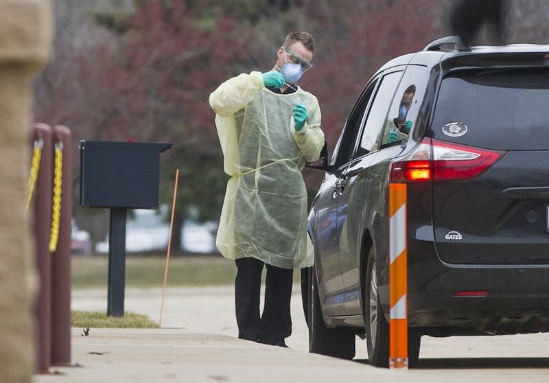 A health care worker tests a patient for the coronavirus in a drive-through site setup outside the South Bend Clinic Day Road Immediate Care Center on Wednesday, March 11, 2020, in Mishawaka, Ind. (Robert Franklin/South Bend Tribune via AP)