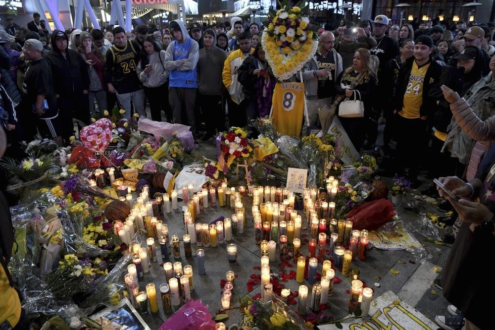 People gather at a memorial near Staples Center Jan. 26, 2020, in Los Angeles after the death of Laker legend Kobe Bryant. (AP Photo/Michael Owen Baker)