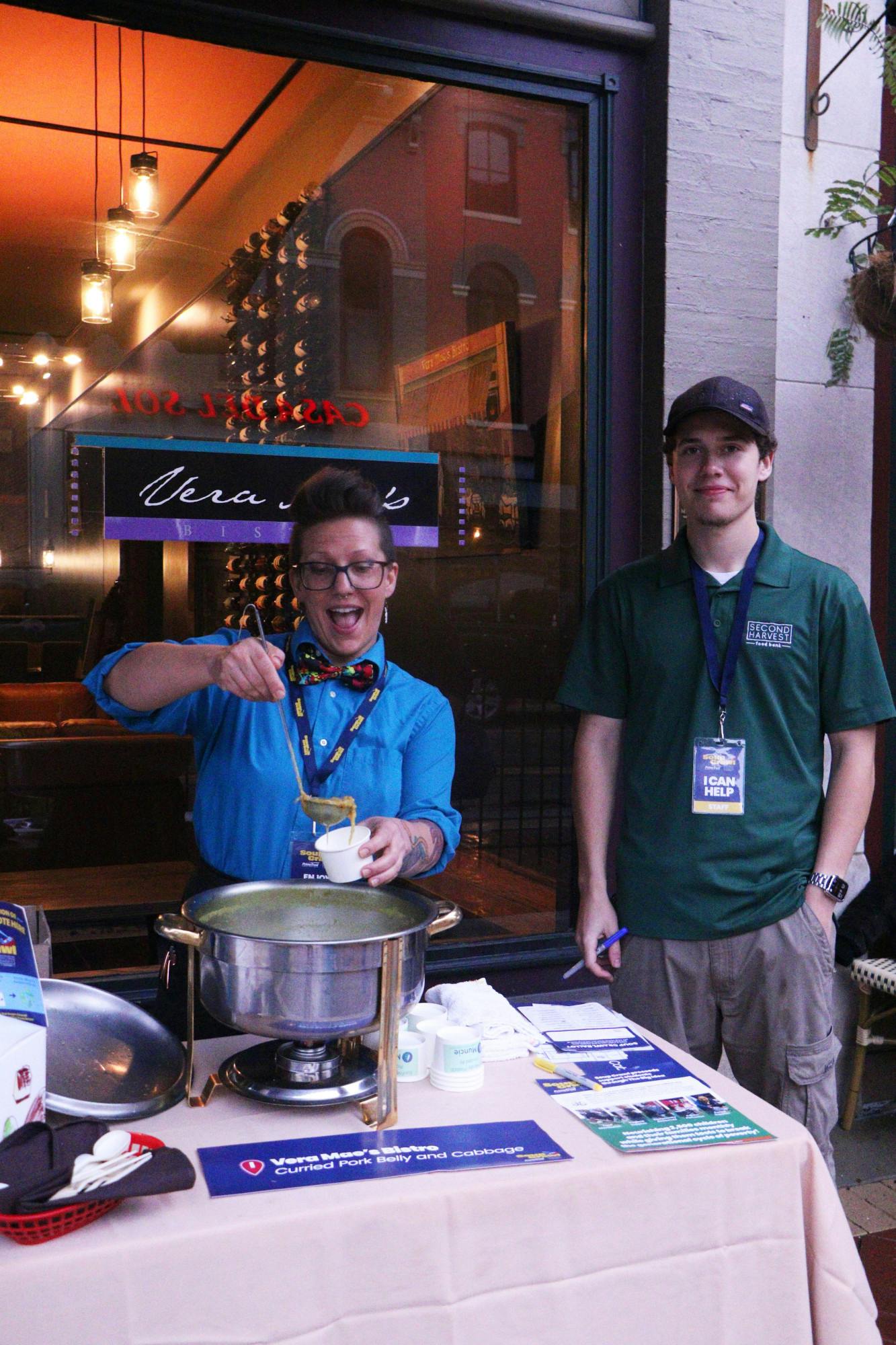 VeraMae’s Bistros’ Melissa Kaderly and Second Harvest staff member Devin Douthitt serve Curried Pork Belly and Cabbage Oct. 5 outside of VeraMae Bistros. The business has been around since 1999 with lunch  delivery and catering as the focus, but became a restaurant in 2002. Ellie Marker, DN