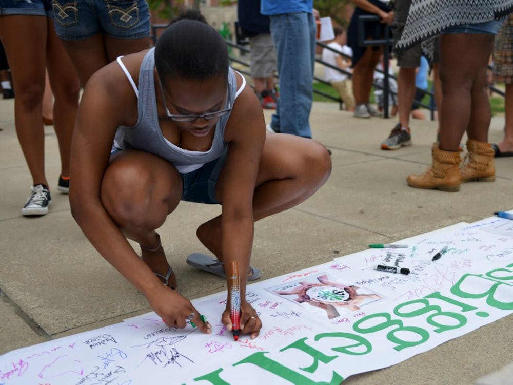 Senior student Joann Darrett signs the #ITBIGGERTHANYOU Banner during the ETA protest on Sunday afternoon at North Quad. The event was meant to embrace the spirit of peace and solidarity.  DN PHOTO SICONG XING
