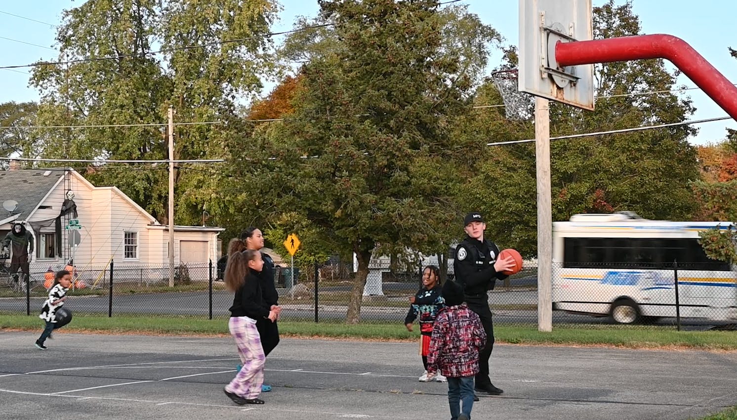 A Muncie police officer plays basketball with community children at Ball Corp Park for Muncie Southside Neighborhood Association basketball &amp; kickball event.