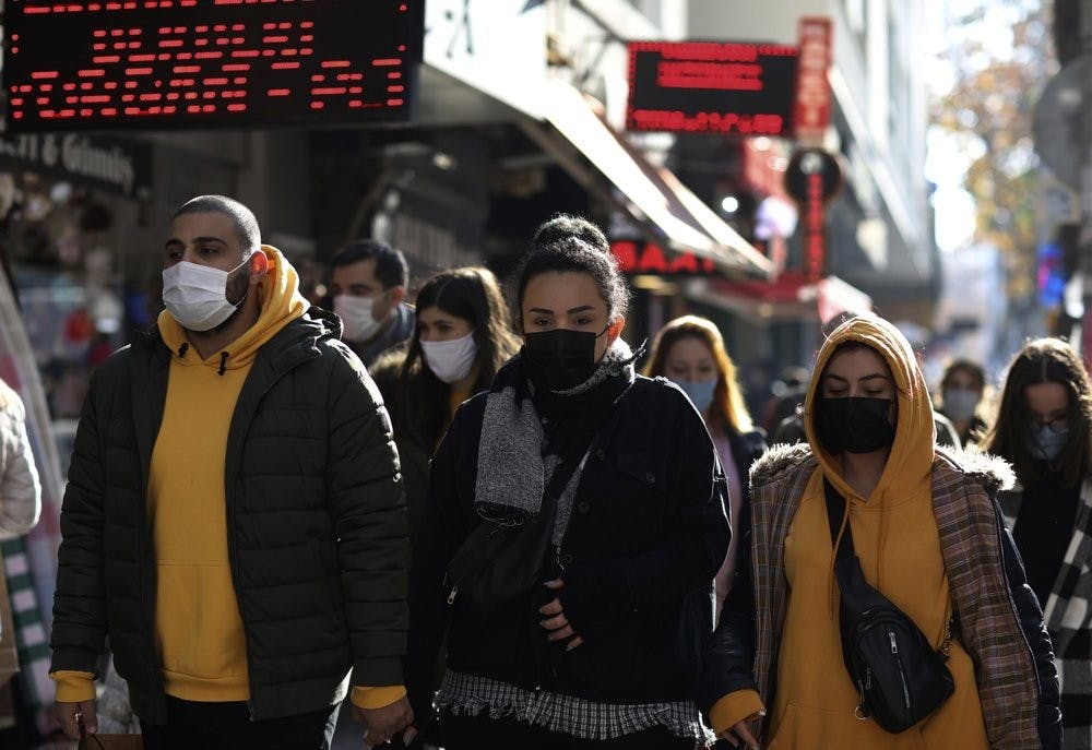 People wearing masks to help protect against the spread of coronavirus, walk in Ankara, Turkey, Friday, Nov. 27, 2020. The official daily COVID-19 deaths have steadily risen to record numbers in a reversal of fortune for the country that had been praised for managing to keep fatalities low. (AP Photo/Burhan Ozbilici)