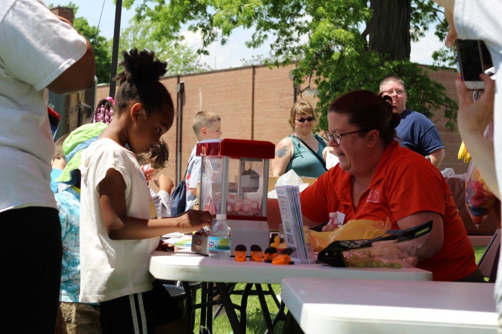 Stacey Ream-Britton, research development coach for Second Harvest Food Bank, works a her station as a participant stands by at Ball State's Community Campus Experience event May 18, 2019, at Heekin Park. Second Harvest distributed fruits to those in attendance. Britney S. Kendrick, DN