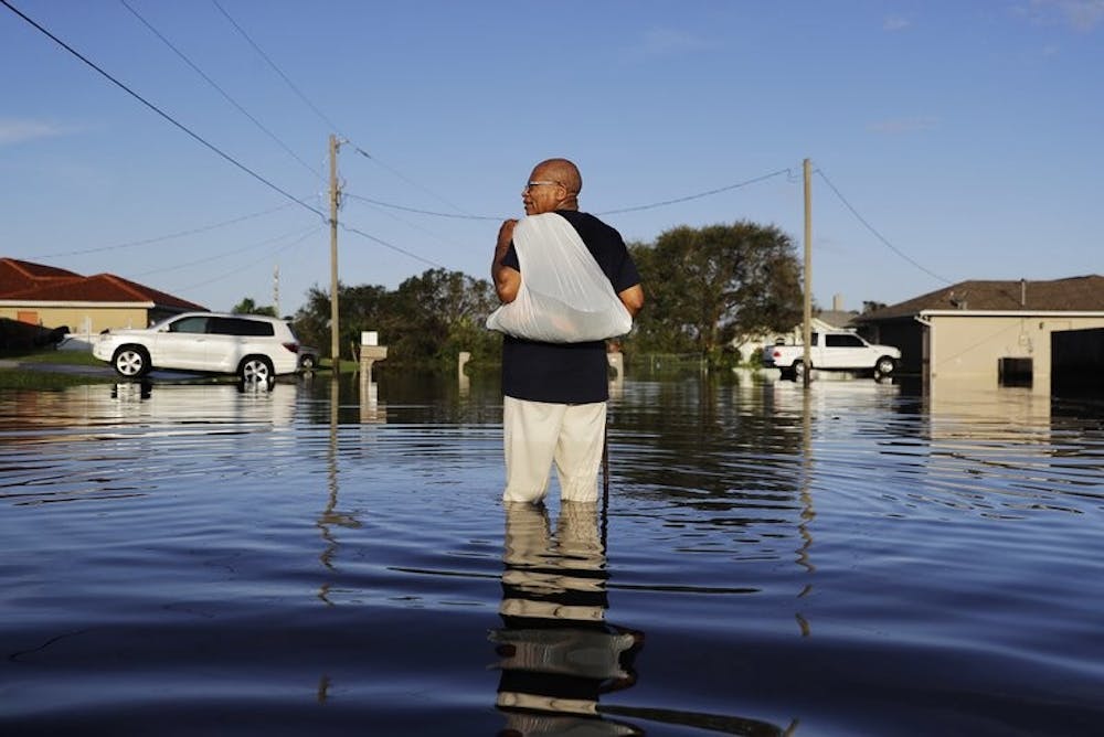 <p>Jean Chatelier walks through a flooded street from Hurricane Irma after retrieving his uniform from his house to return to work today at a supermarket in Fort Myers, Fla., Tuesday, Sept. 12, 2017. Chatelier walked about a mile each way in knee-high water as a Publix supermarket was planning on reopening to the public today. “I want to go back to work. I want to help,” said Chatelier. <strong>David Goldman, Associated Press</strong></p>