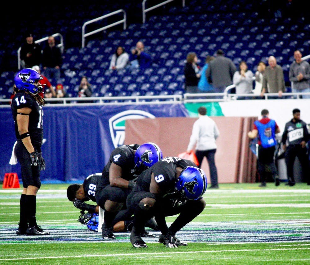 <p>Seniors Khalil Hodge, Cameron Lewis, Brandon Williams and Tatum Slack kneel in disbelief as Bulls lose MAC title game.&nbsp;</p>