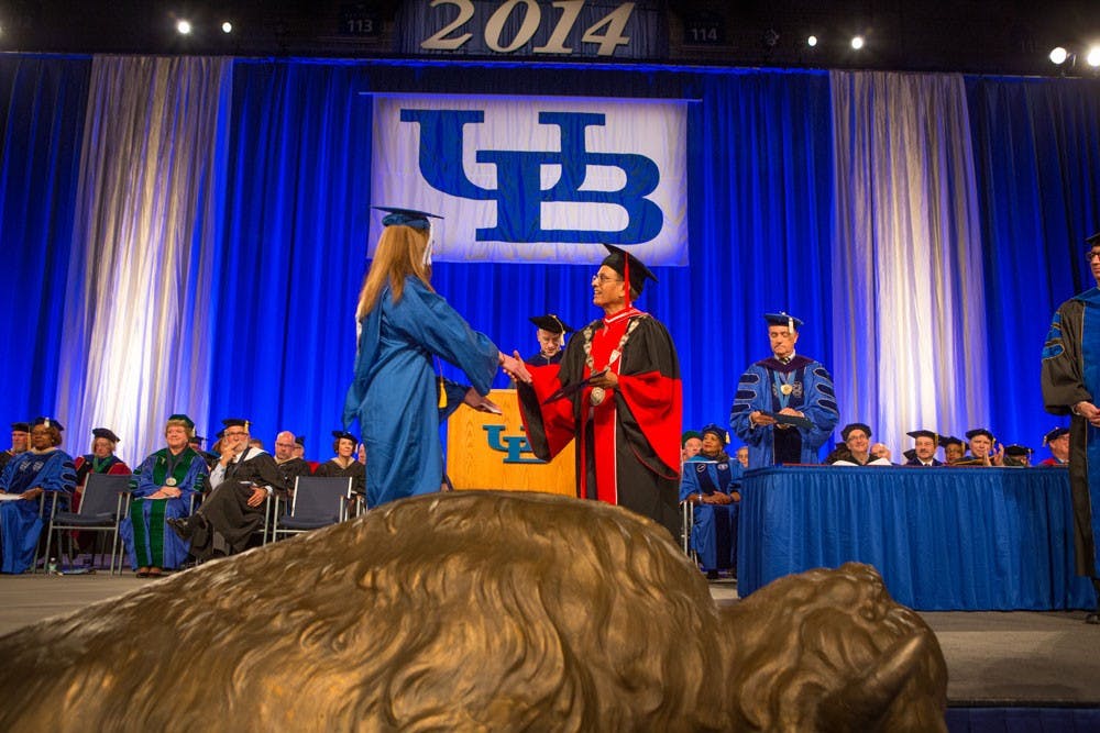 <p>A student shakes&nbsp;UB President Satish Tripathi's hand during a graduation ceremony. Some students say walking at graduation symbolizes their hard work during college while others feel as though it is just a hassle.&nbsp;</p>
