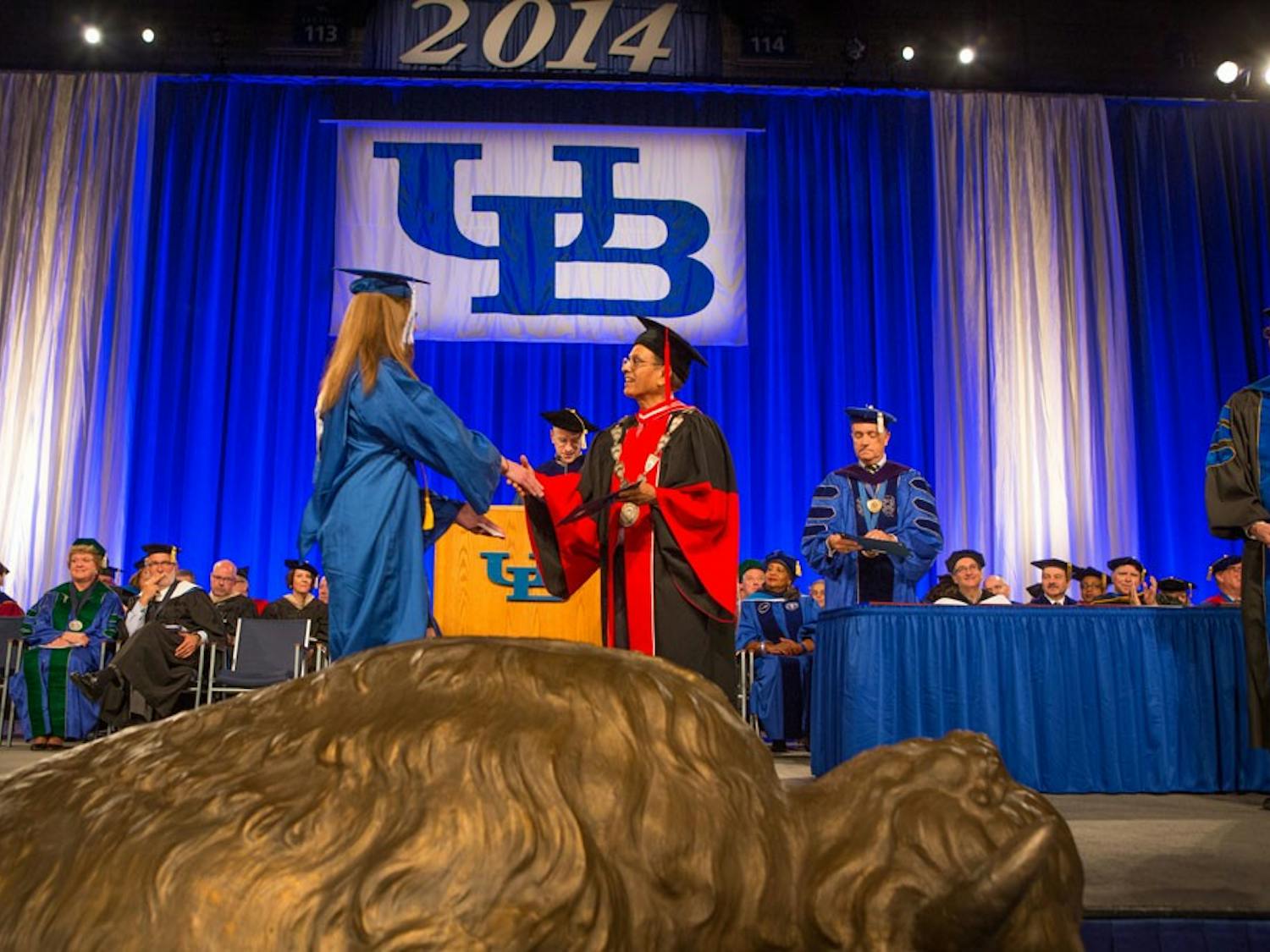 A student shakes UB President Satish Tripathi's hand during a graduation ceremony. Some students say walking at graduation symbolizes their hard work during college while others feel as though it is just a hassle. 