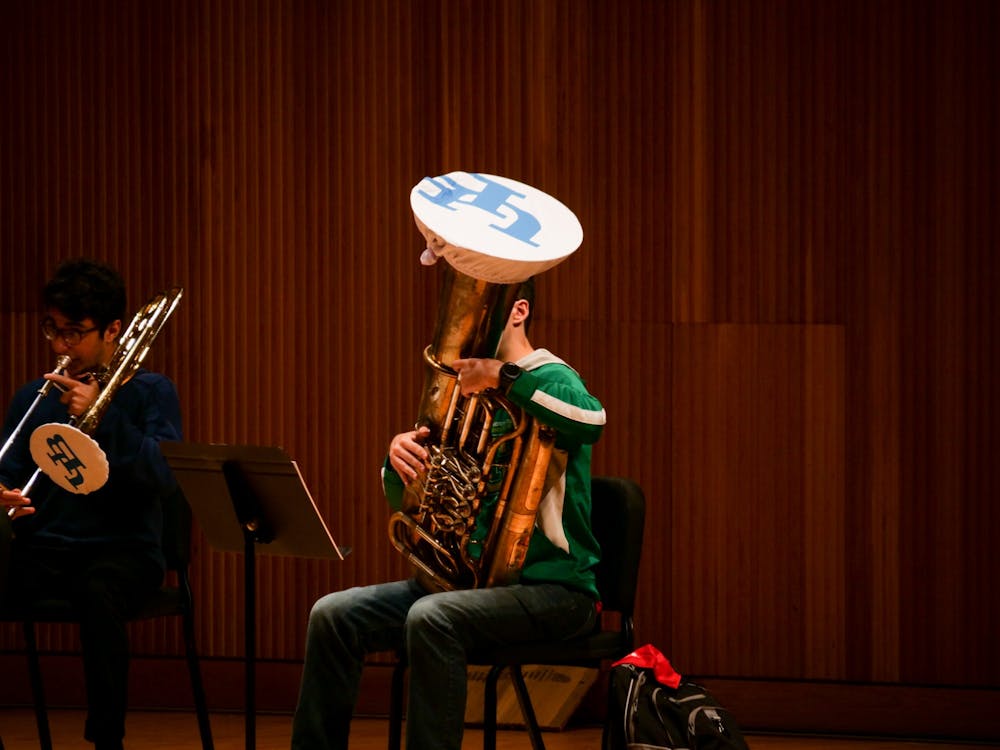 <p>A UB band student using a fabric cover on their instrument to prevent the spread of aerosols</p>