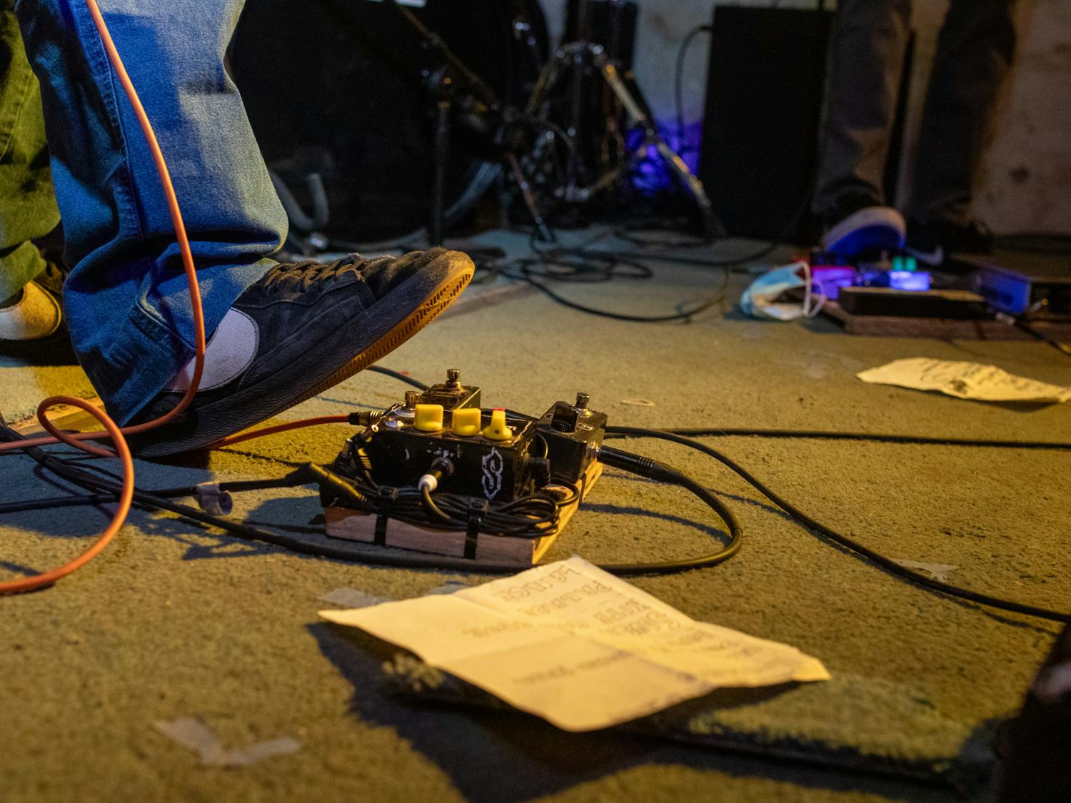Guitar pedals, cables, and setlists litter the makeshift pallet stage at The Lavender Room.