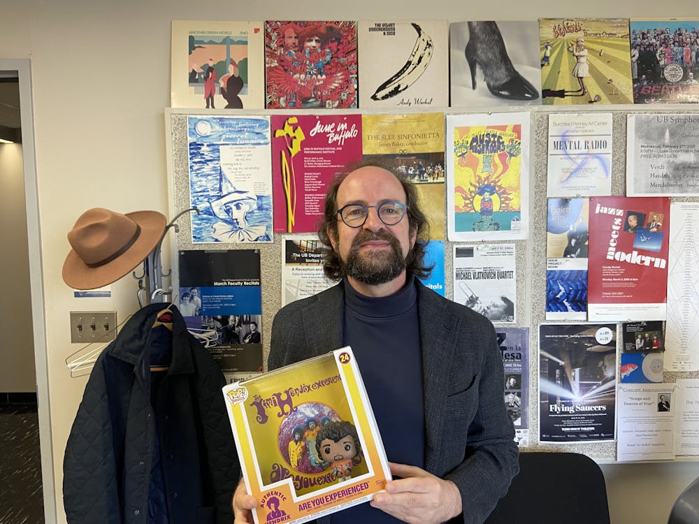 <p>Jonathan Golove poses in his office with a Jimi Hendrix figurine gifted to him by students of MUS 365: "Rock Music".</p>