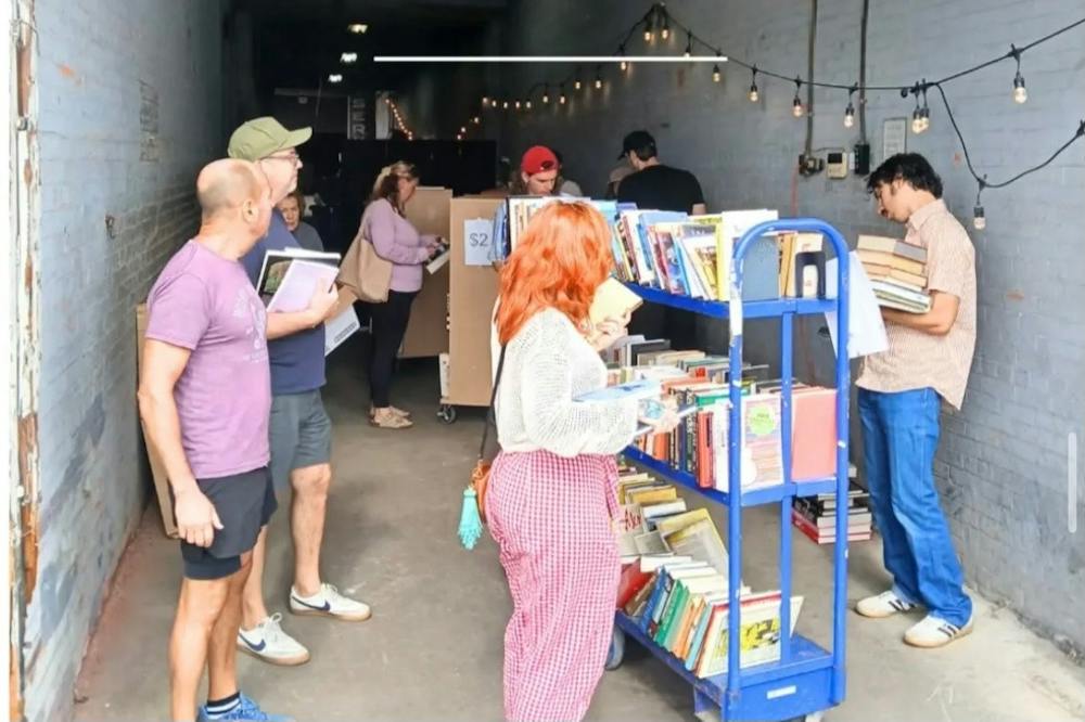 <p>Customers crowd around the $1 book sale on the sidewalk at Fitz Books &amp; Waffles.&nbsp;</p>