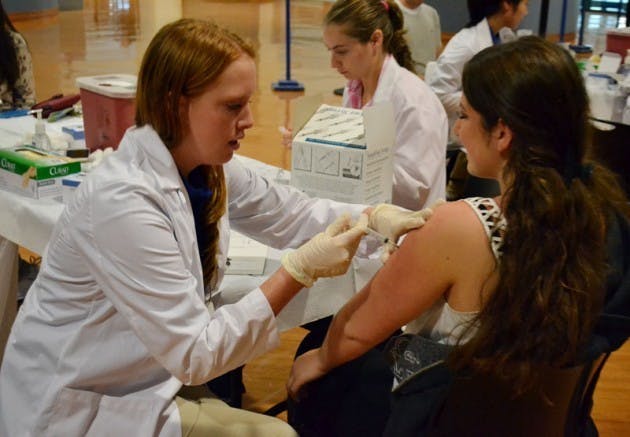 Elana Cwass (right), a junior health and human services major, received a flu shot from Stephanie Magnani (left), a junior nursing major, at an open clinic on Tuesday, which were held through Friday. UB students have to pay $10 to receive the vaccine, which covers the cost of the actual vaccine, this year and the year before. Cwass said she was surprised she had to pay the fee, and she said more students would get the vaccine if it was free.&nbsp;Lily Weisberg, The Spectrum