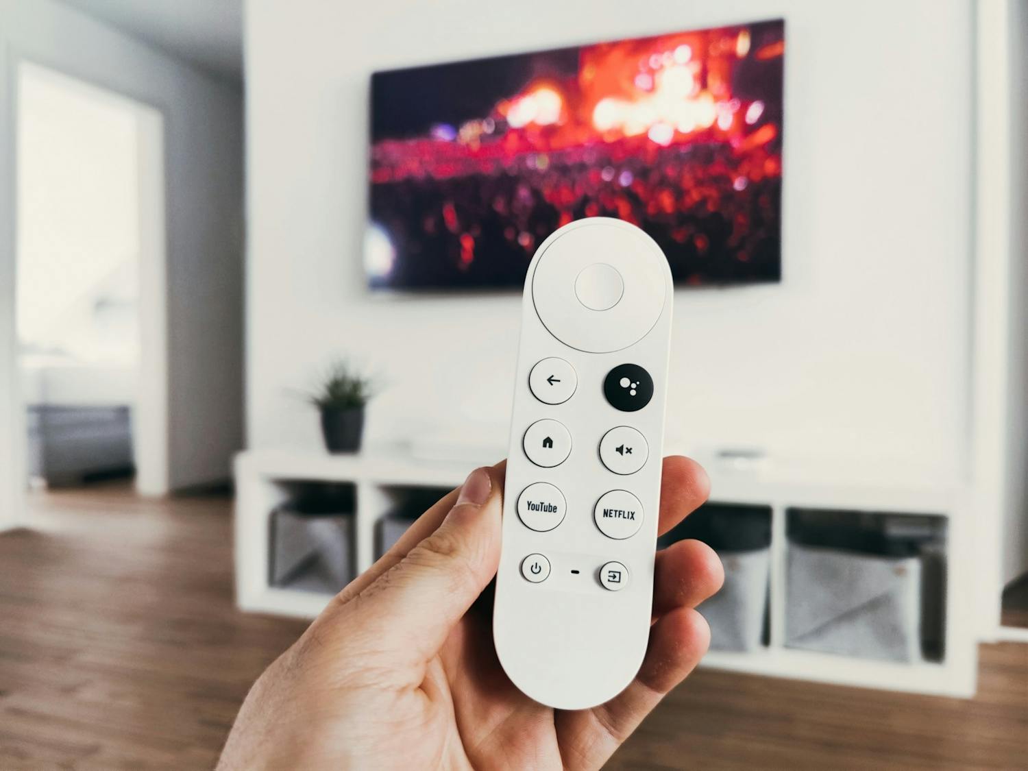 A person holds a remote in front of their TV screen.