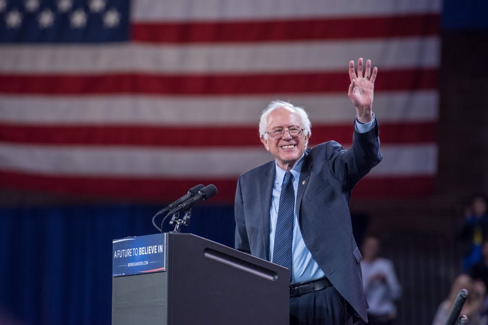 <p>Bernie Sanders waves to the crowd during his "A Future to Believe in Rally" at Alumni Arena Monday evening.&nbsp;</p>