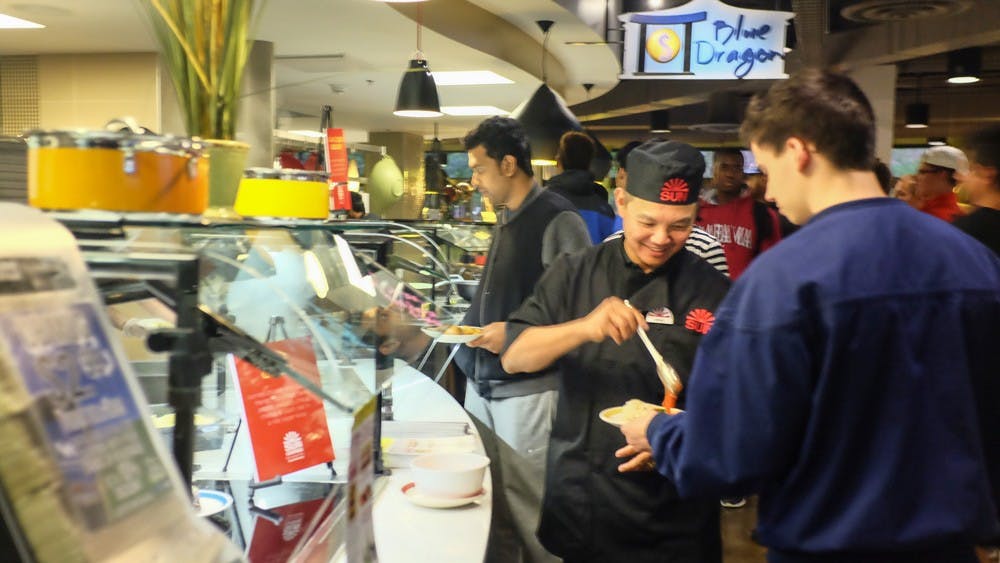 <p>The owner of Sun Restaurant Kevin Lin (middle) serves a student in C3 during Tuesday's dinner time. C3 is teaming up with local restaurants to bring new foods to the dining hall. </p>