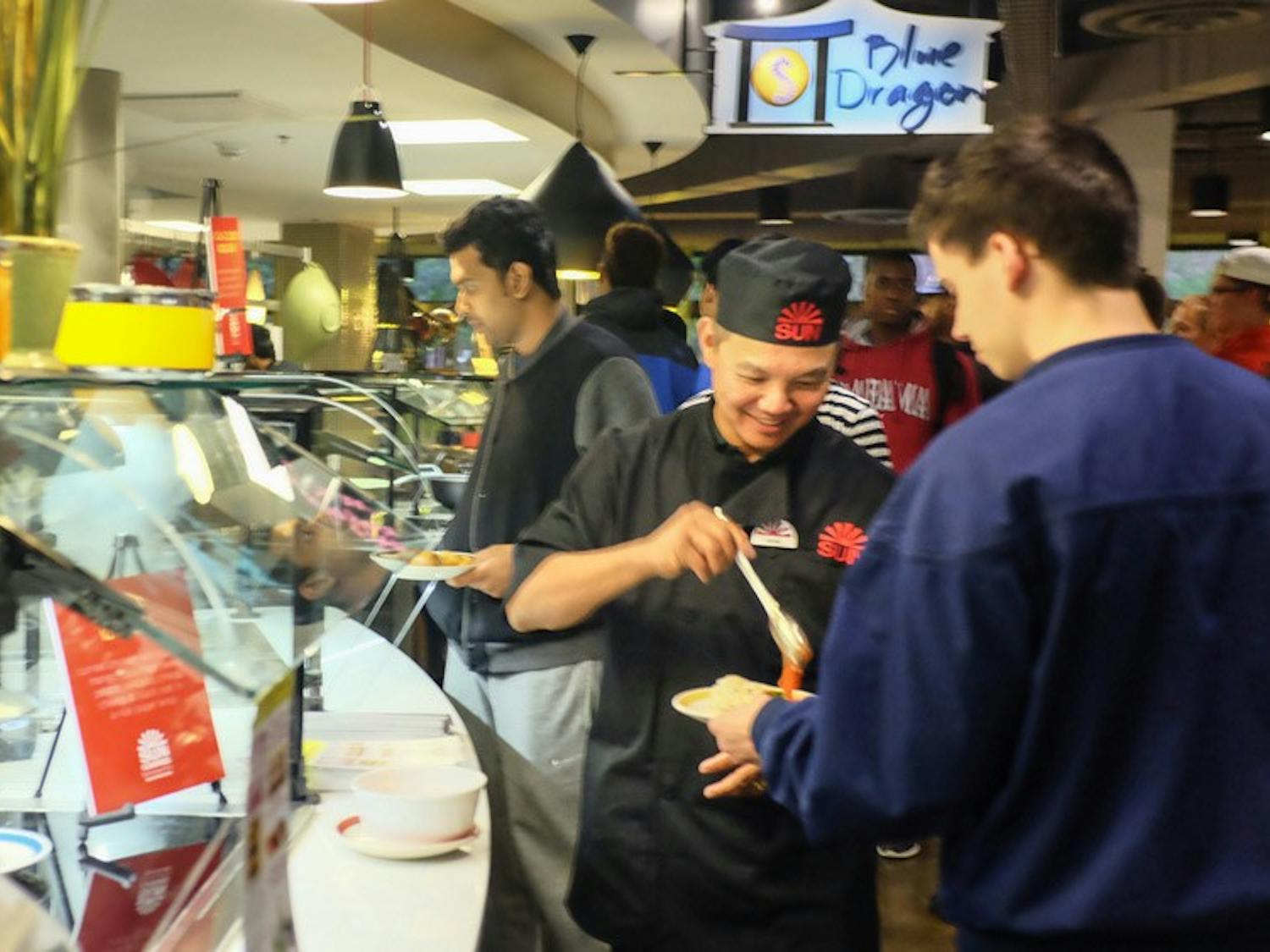 The owner of Sun Restaurant Kevin Lin (middle) serves a student in C3 during Tuesday's dinner time. C3 is teaming up with local restaurants to bring new foods to the dining hall.