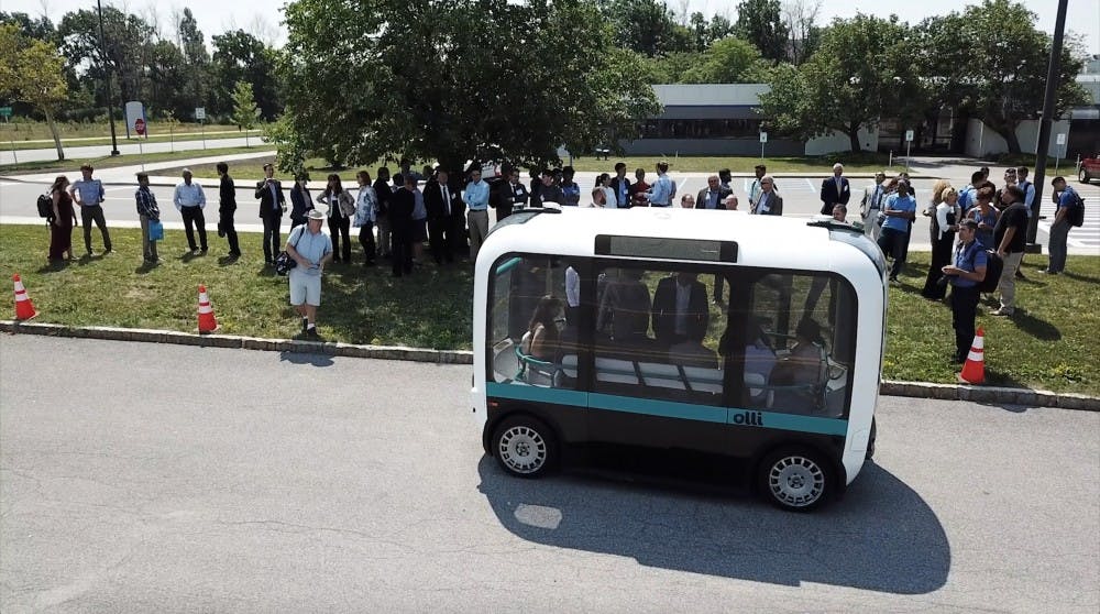Members of the UB community checking out the Olli bus in the Center for Tomorrow parking lot before a demo on its test course. The self-driving shuttle will be the subject of a two-year study exploring its economic feasibility and safety features.