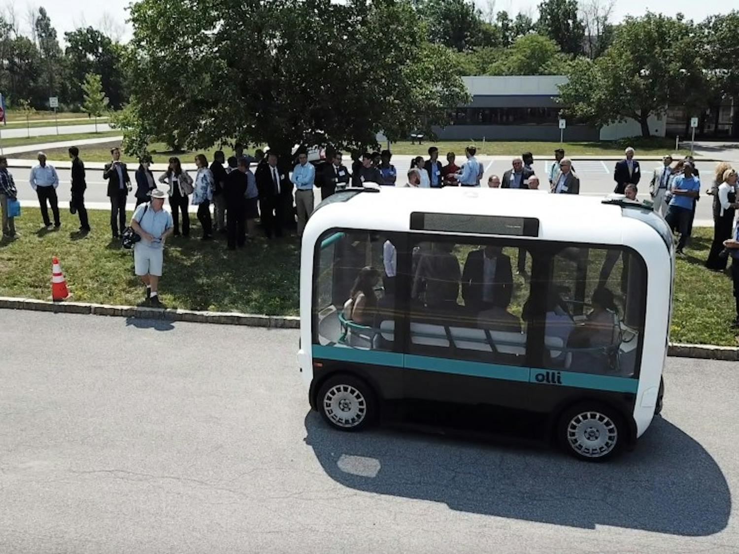 Members of the UB community checking out the Olli bus in the Center for Tomorrow parking lot before a demo on its test course. The self-driving shuttle will be the subject of a two-year study exploring its economic feasibility and safety features.