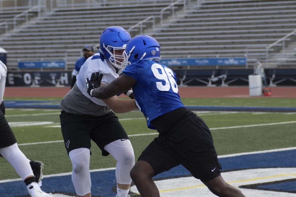 <p>UB defensive end Jordan Avissey holds back offensive lineman during an early season practice.</p>