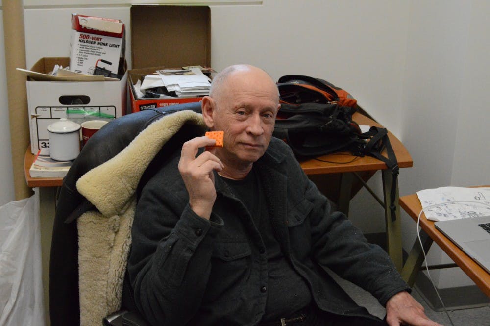<p>UB professor David Schirm enjoys a cheese and peanut butter cracker in his office. Schirm, a celebrated artist and tenured professor, is set to retire in 2020.</p>