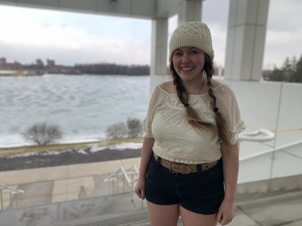 <p>Anna Seidl stands in front of ice-covered Lake LaSalle. The theater performance student has built a local reputation for wearing shorts during the winter.</p>