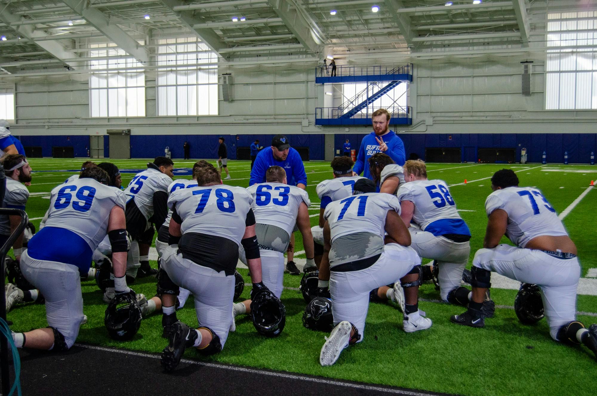 Members of the offensive line crowd receive instruction from their coaches on a recent day of spring practice.