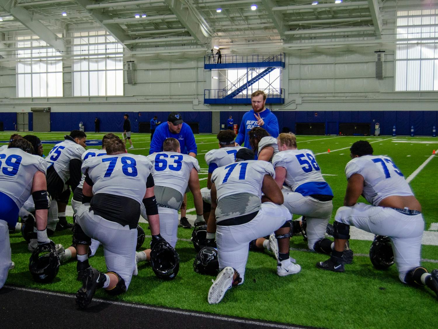 Members of the offensive line crowd receive instruction from their coaches on a recent day of spring practice.