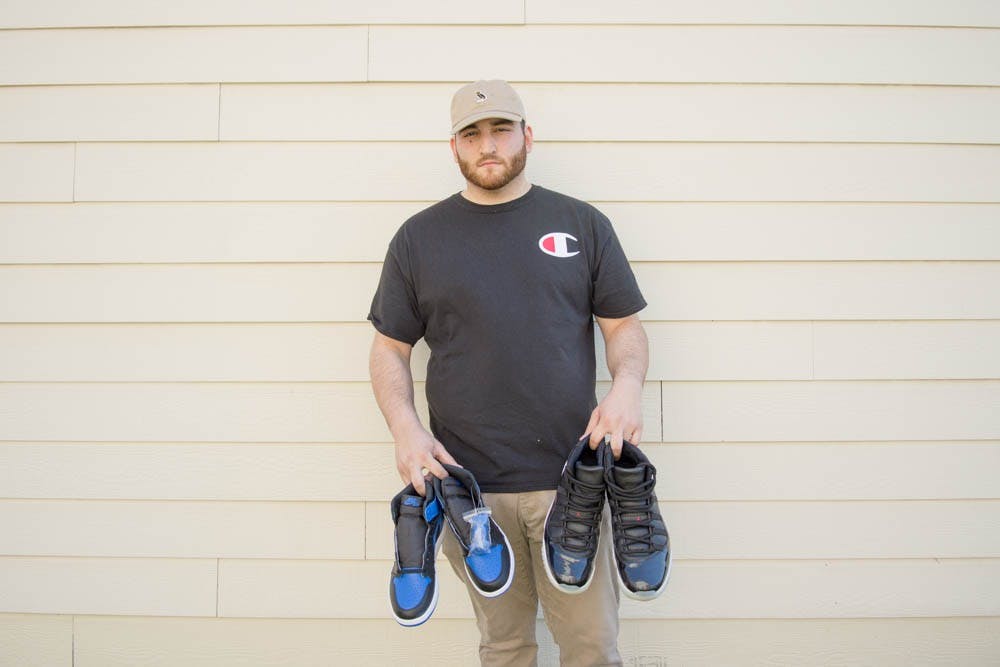 <p>Senior finance student Evan Tirsun holds a Jordan 1 Royal sneaker outside of his apartment. Tirsun frequently buys expensive pairs of shoes when they first release and sells them online for a profit.</p>