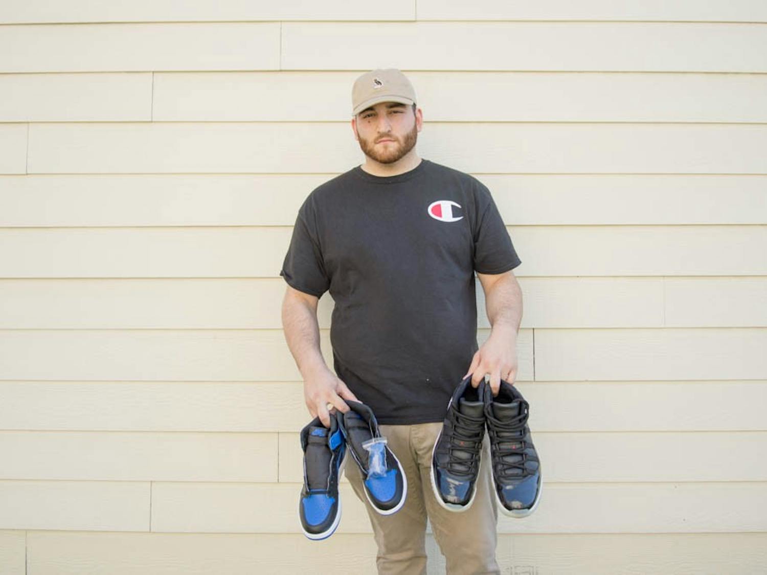 Senior finance student Evan Tirsun holds a Jordan 1 Royal sneaker outside of his apartment. Tirsun frequently buys expensive pairs of shoes when they first release and sells them online for a profit.