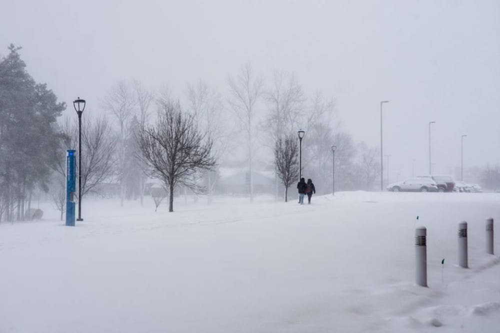 <p>Two students make their way toward the Center for Arts parking lot in the snowy weather Friday afternoon. The weather caused at least&nbsp;two accidents, according to University Police.&nbsp;</p>