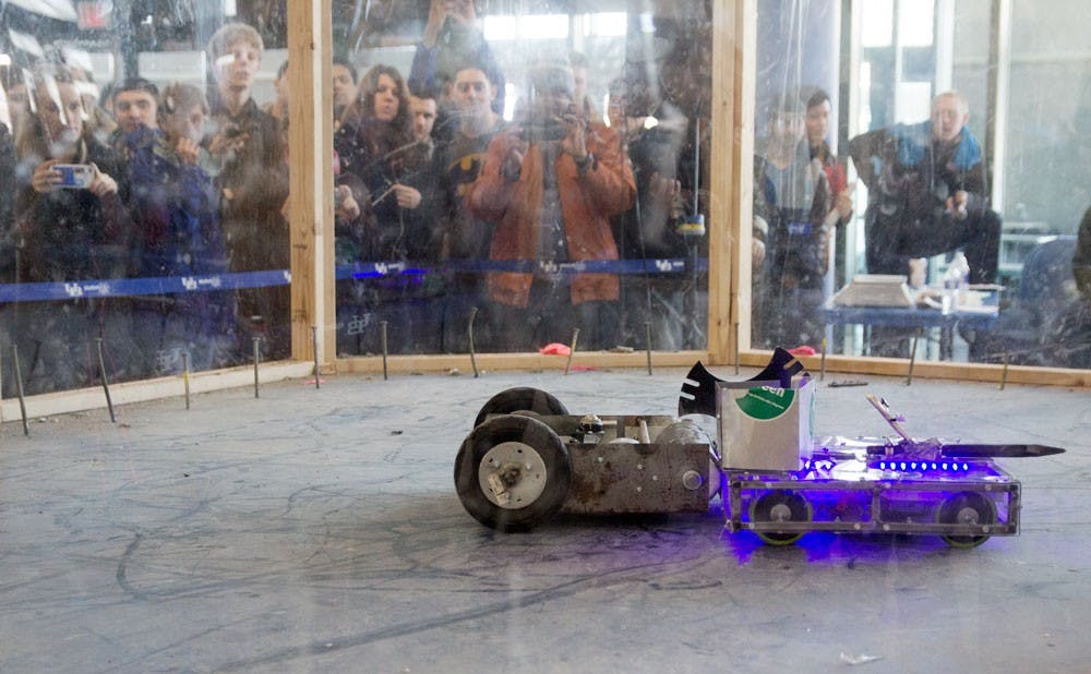 <p>UB students look on and take pictures of two robots battling for a win during "Bot Wars," an Engineering Week event held Friday in the Student Union.</p>