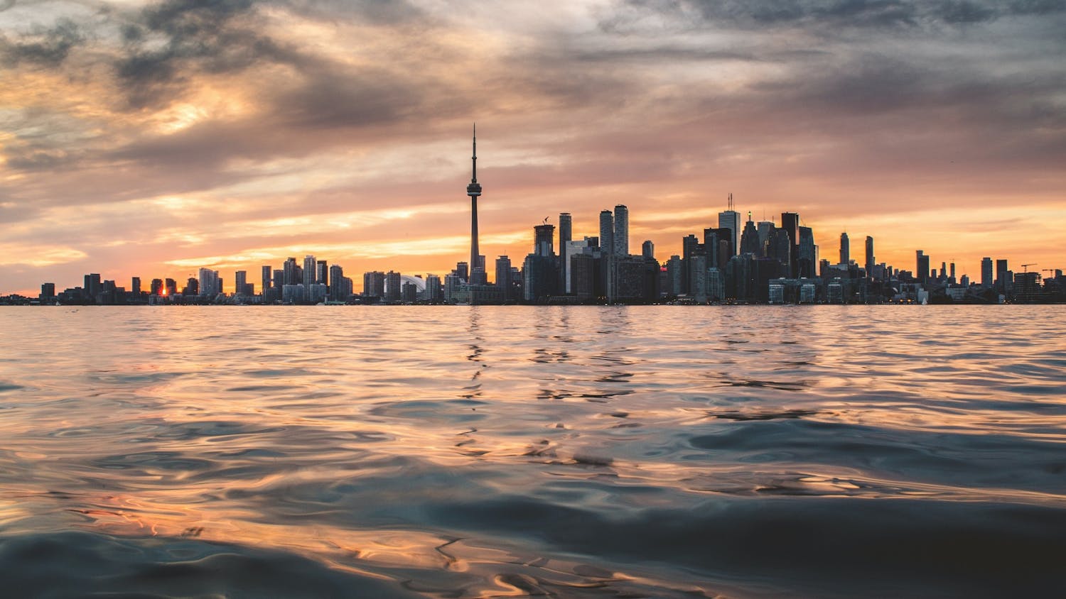 Toronto looms large over a body of water. Students should go to Canada with “literal strangers,” writes Reilly Mullen.