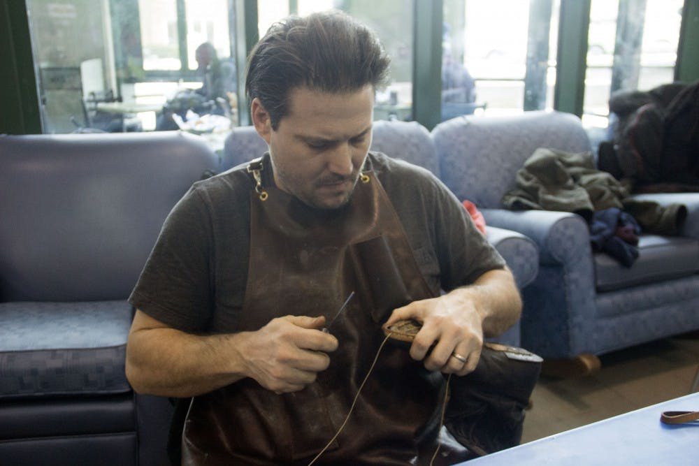 <p>Brian “Sole Man” Gavigan repairs a shoe during the Points of Intervention (POI) tour in SU. Gavigan and other repairers aimed to fix everything from watches to laptops at this year’s fair.</p>