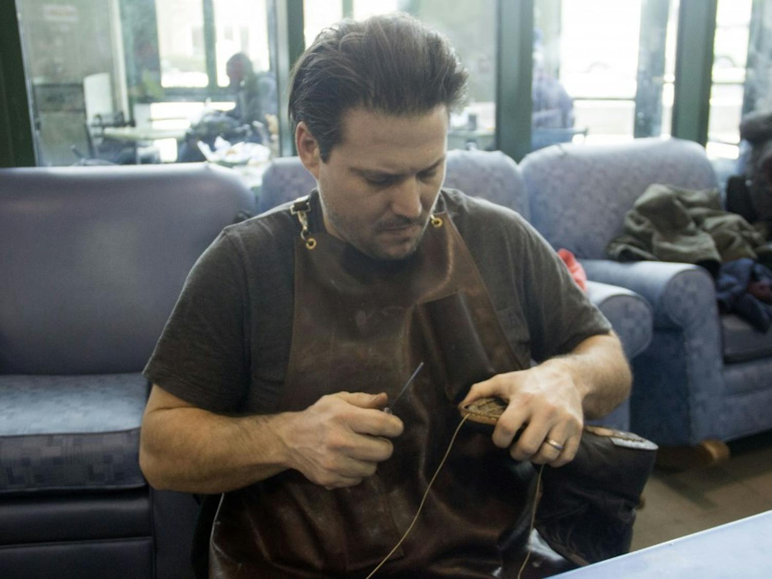 Brian “Sole Man” Gavigan repairs a shoe during the Points of Intervention (POI) tour in SU. Gavigan and other repairers aimed to fix everything from watches to laptops at this year’s fair.