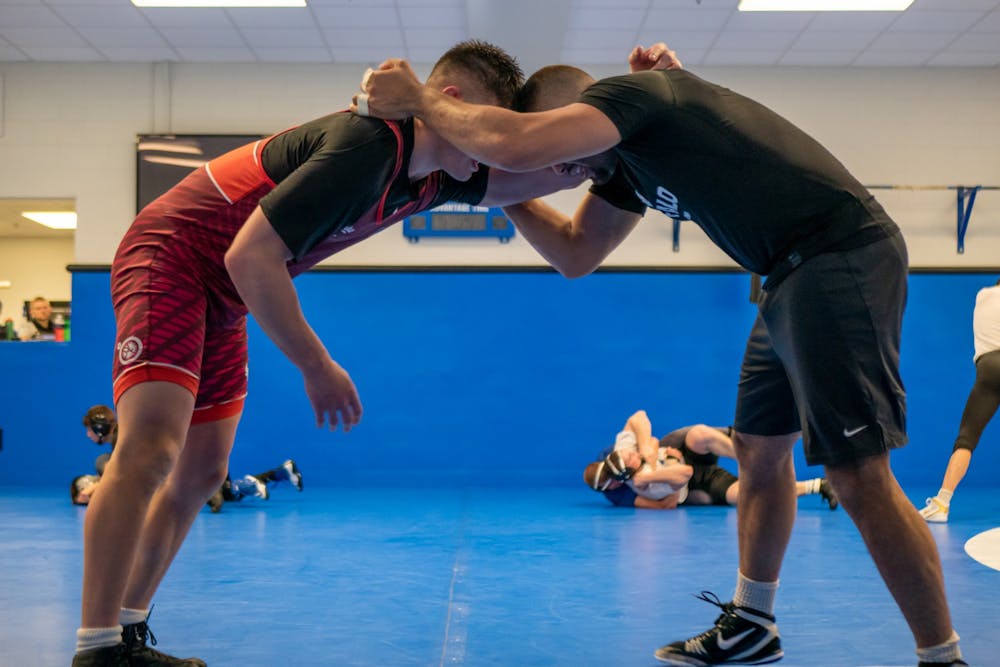 <p>Wrestlers practice their drilling positions during warmup.</p>