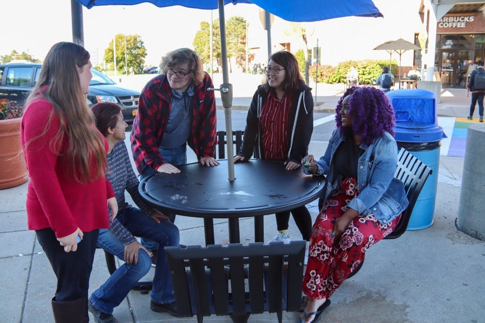 <p>The cosplay club eboard discusses upcoming meetings in front of the Student Union.</p>
