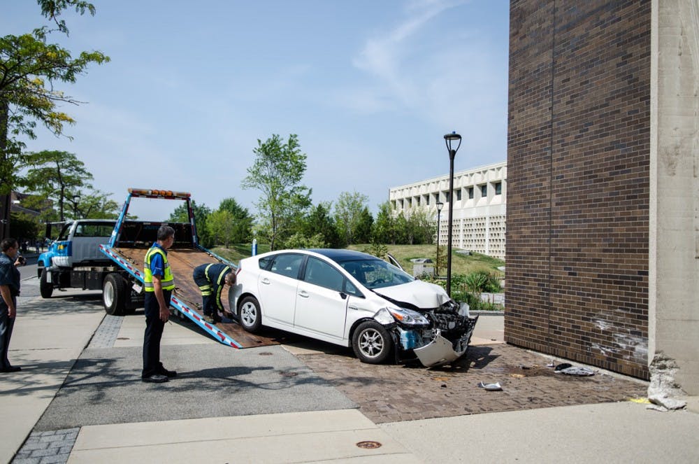<p>A car is towed away from Furnas Hall after it crashed into the building Tuesday. </p>