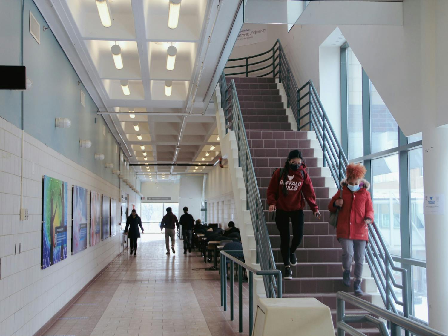 Students descend the Natural Sciences Complex stairs in masks.