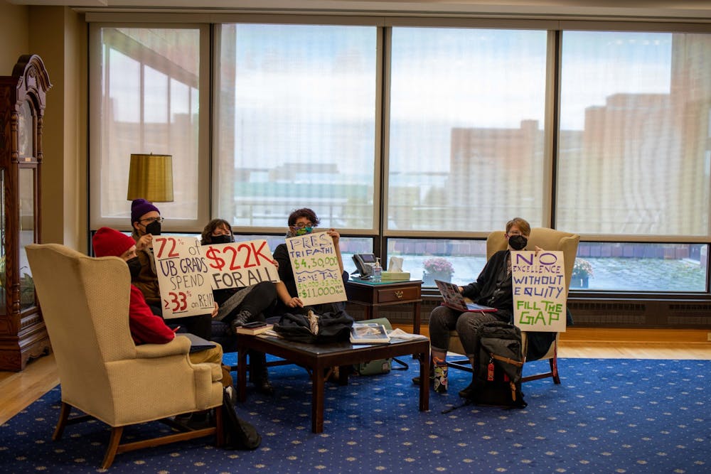 Students hold up signs outside President Tripathi’s office last semester.