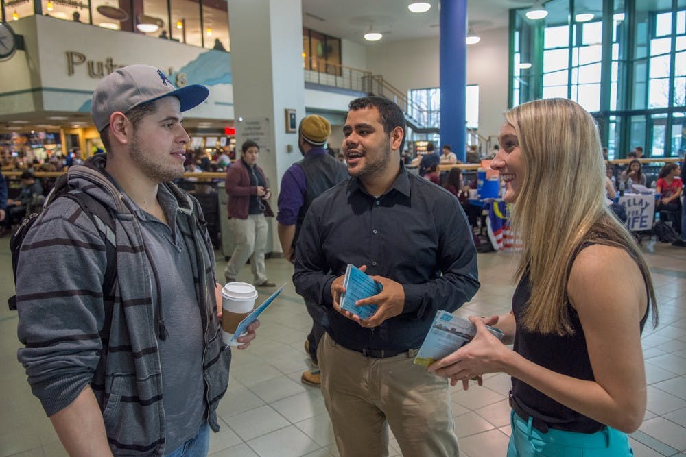<p>Progress Party president candidate Matt Rivera (center) and vice president candidate Megan Glander (right) campaign in the Student Union during the last day of voting for the&nbsp;Student Association elections on Thursday. Exit poll numbers indicate the Progress Party has received the majority of student votes.&nbsp;</p>